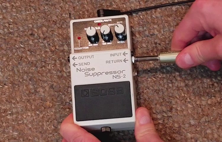 man connects boss noise pedal